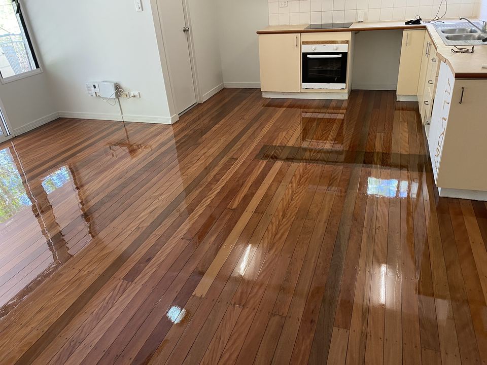 The same kitchen after sanding and polishing, with rich red-brown boards and a high-gloss finish.