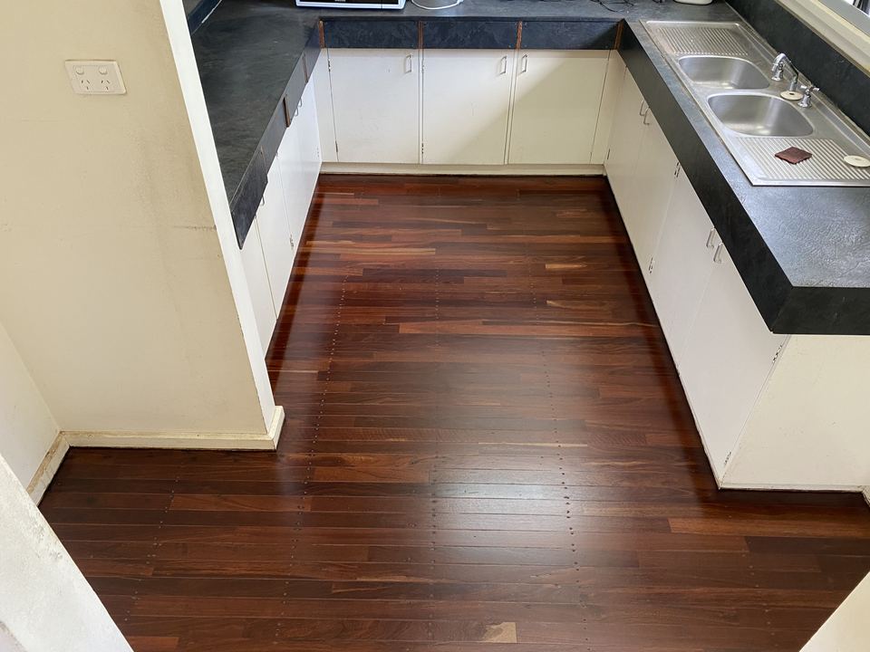 The same kitchen after sanding and polishing, with deep red timber boards.