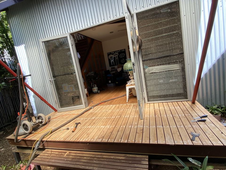 Freshly coated deck outside a corrugated iron home.