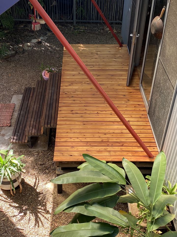 Timber deck boards framed by tropical plants.