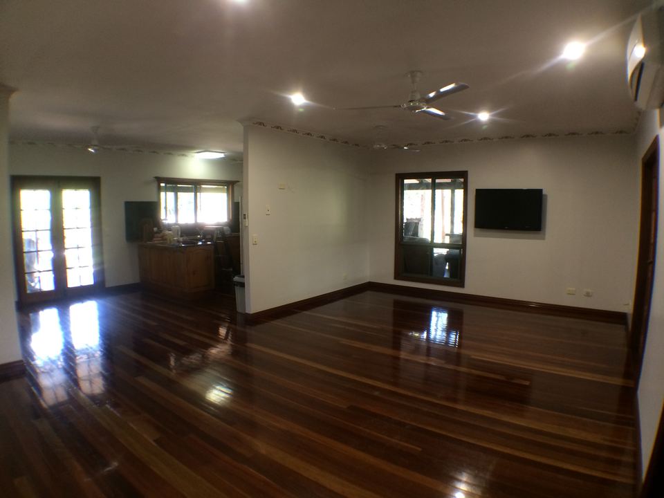 Polished hardwood floor in a large open-plan room with French doors.