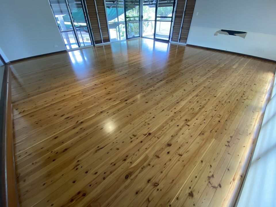 Polished pine floor in a bright living room with sliding doors.