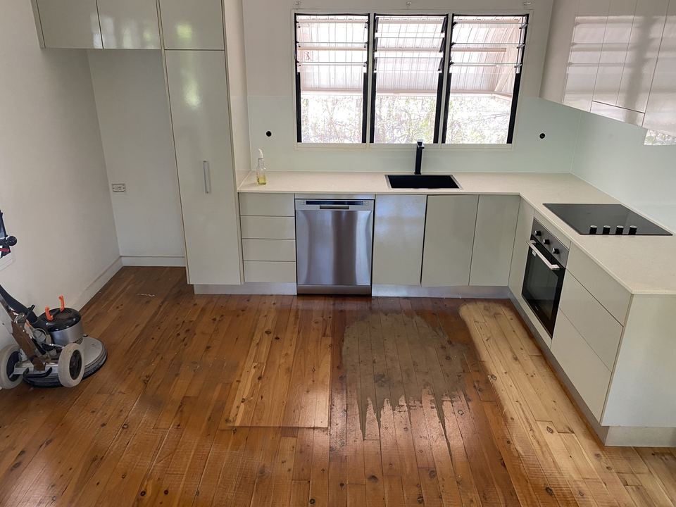 Pine kitchen floor part way through coating, with the sanding machine at left.