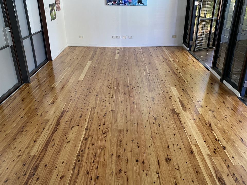 Pine floor with natural knots, sanded and polished in an open room.