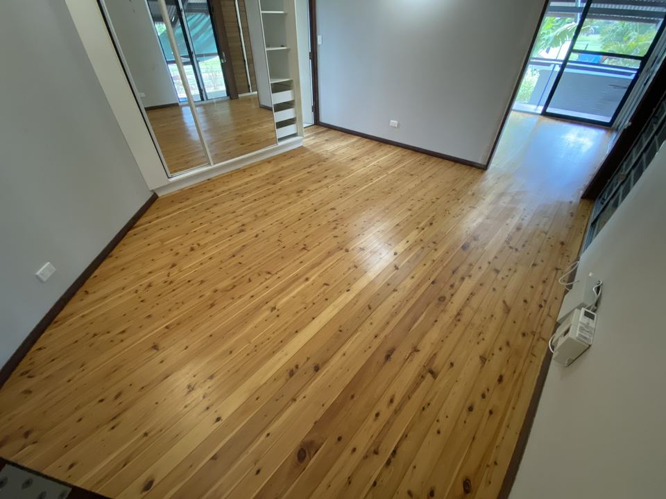 Polished pine floor in a room with sliding glass doors.