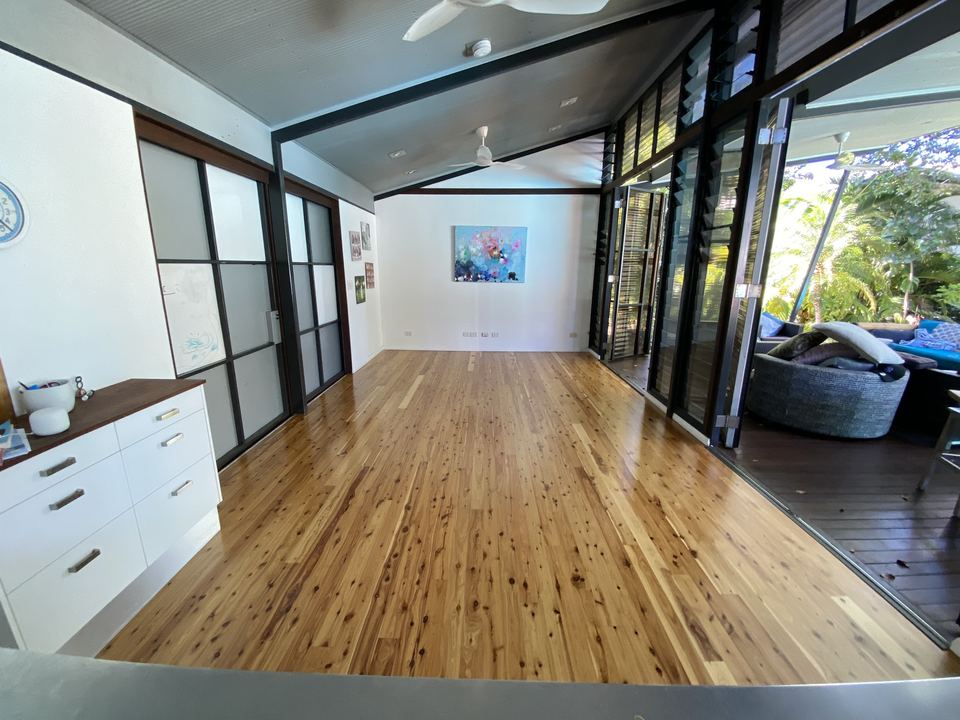 Polished pine floor in an open living area with large windows.