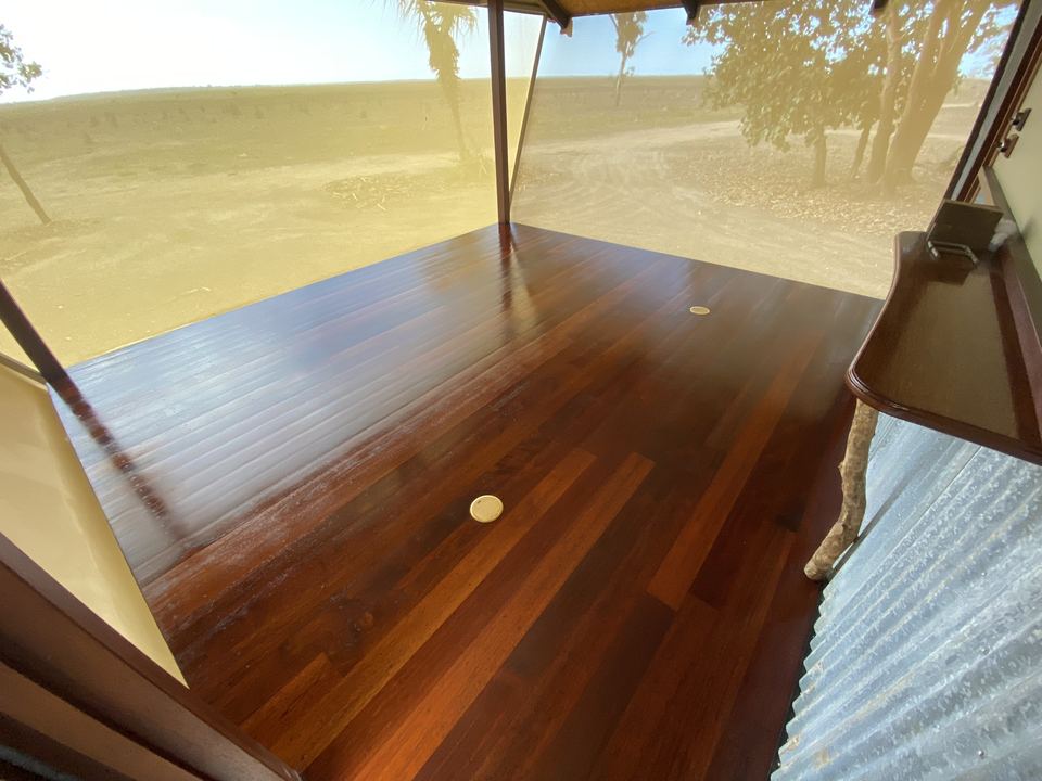 Polished red hardwood floor beside a large window.