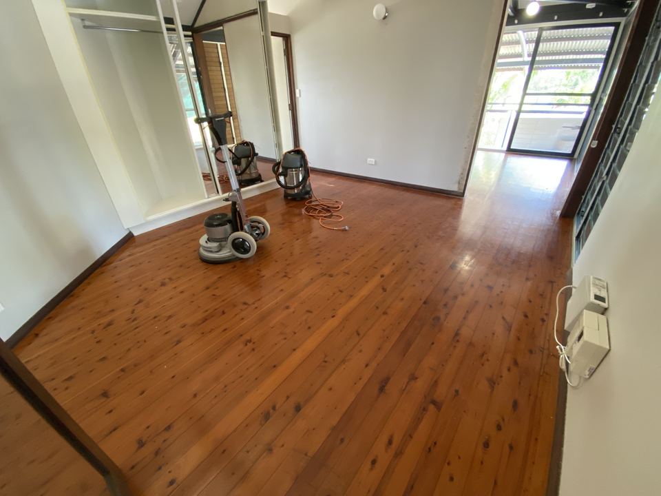 Sanding equipment in a room with a freshly polished hardwood floor.