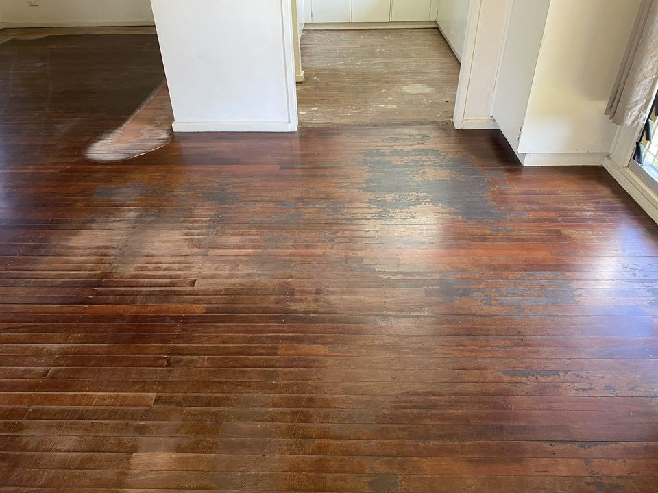 Glossy red-brown hardwood floor seen through a doorway.