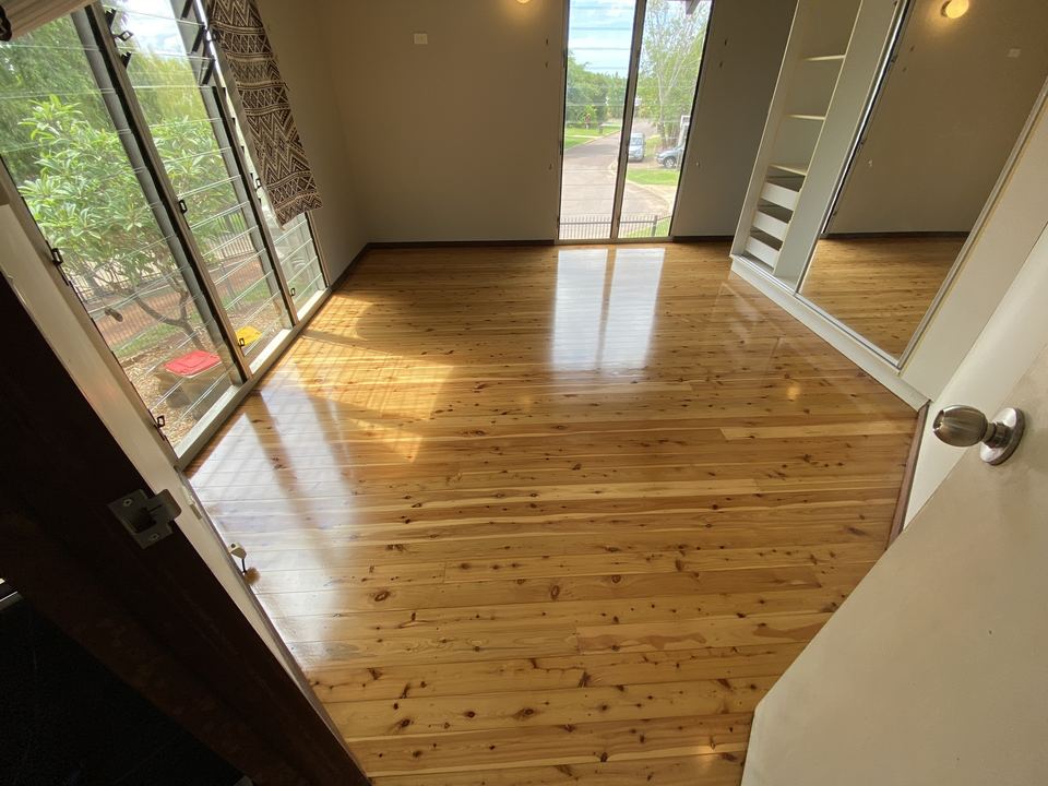Polished golden timber floor in a room with a sliding door to the garden.