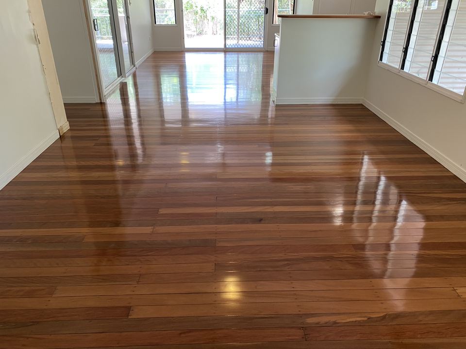 Glossy red-brown hardwood floor through a kitchen and living area.