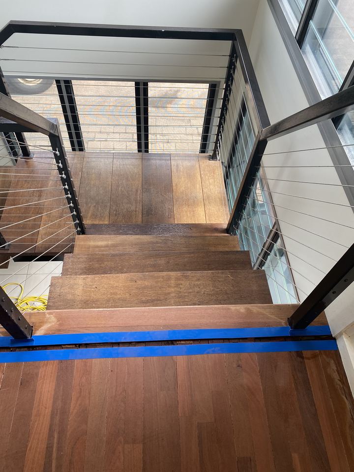 Timber stair treads during preparation, with masking tape along the bottom step.