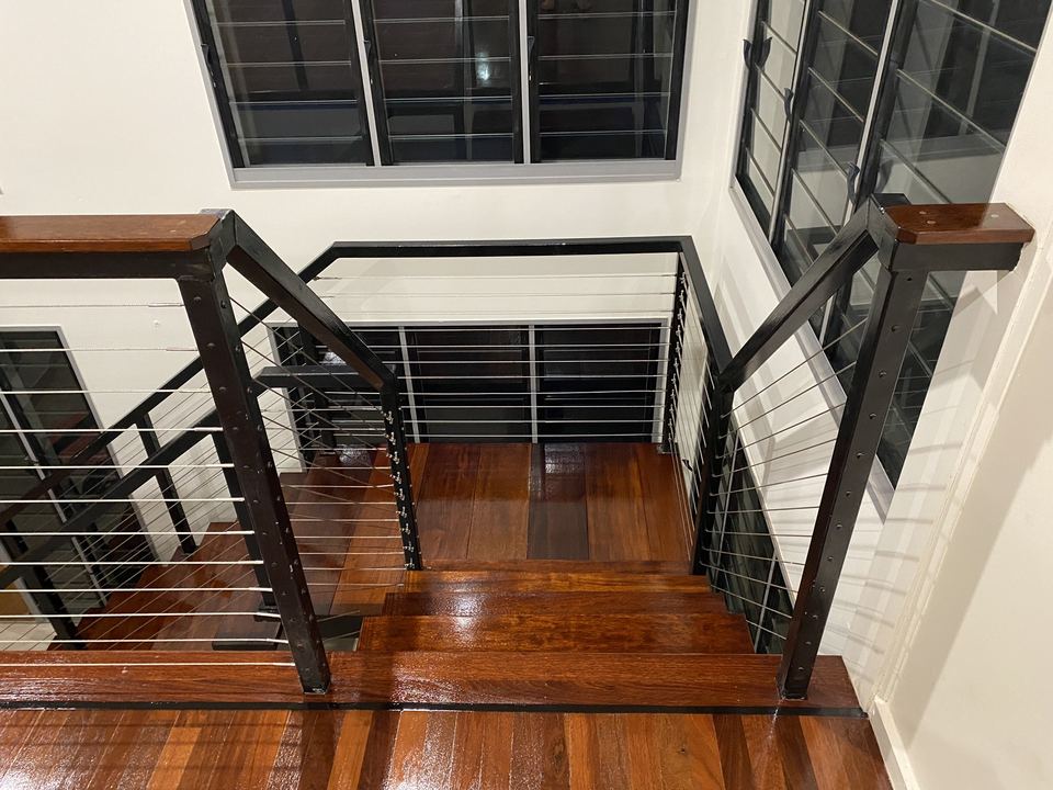 Polished timber stair landing with a black steel balustrade.